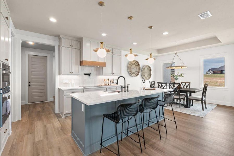 Kitchen featuring hanging light fixtures, a breakfast bar area, backsplash, light wood-style floors, and recessed lighting Kitchen featuring hanging light fixtures, a breakfast bar area, backsplash, light wood-style floors, and recessed lighting