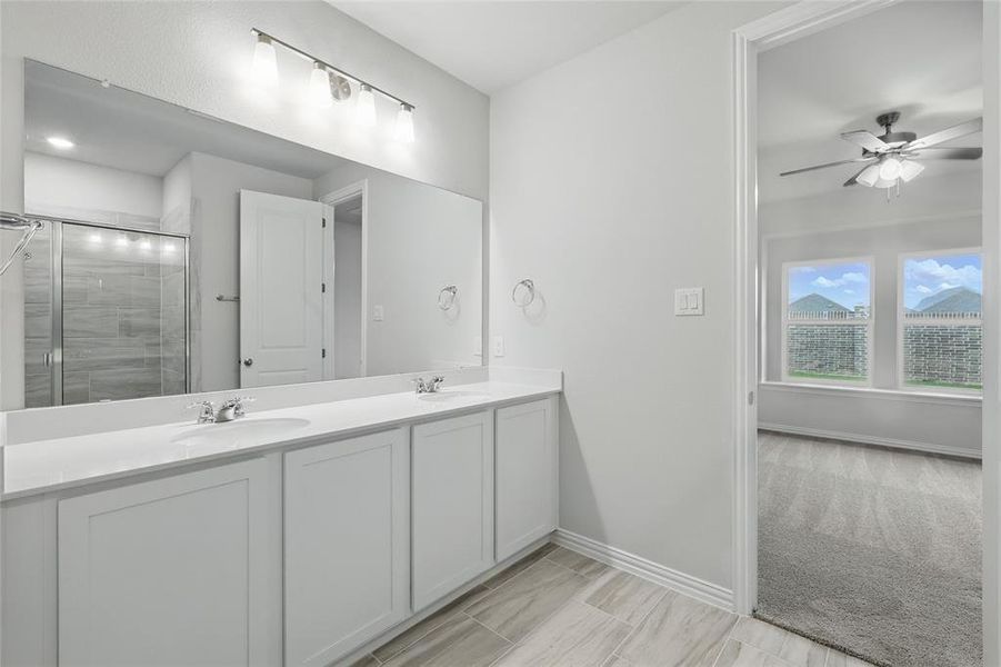Bathroom featuring double vanity, a shower stall, and a ceiling fan