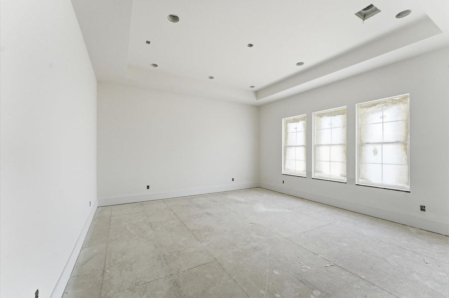 Primary bedroom features a tray ceiling that adds architectural style.