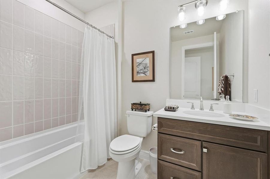 Bathroom featuring shower / bath combo, vanity, and light tile patterned flooring