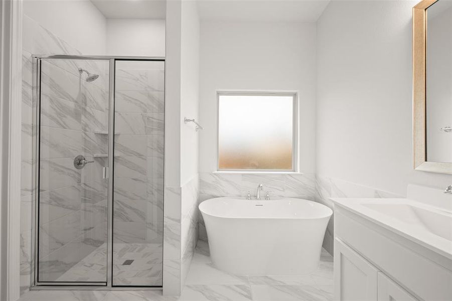 Full bathroom featuring a shower stall, a freestanding tub, vanity, and marble finish flooring
