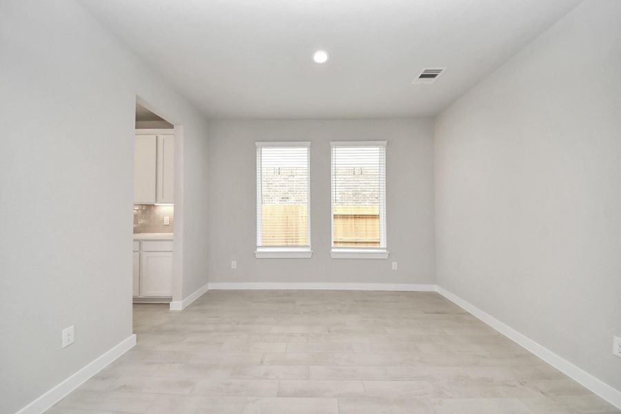 Create lasting memories with your family and friends at the dining table! This expansive dining room showcases sophisticated flooring, custom paint, and seamlessly connects to the family room and kitchen, providing an open and inviting atmosphere.