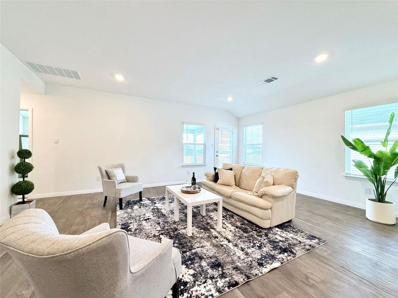 Living room featuring wood finished floors, recessed lighting, and vaulted ceiling Living room featuring wood finished floors, recessed lighting, and vaulted ceiling