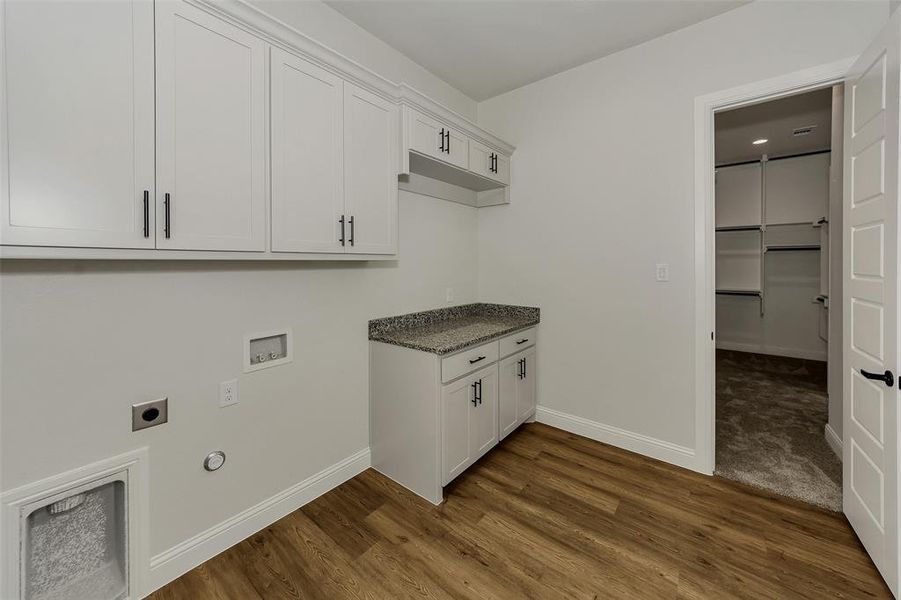Washroom featuring electric dryer hookup, washer hookup, cabinet space, dark wood-style flooring, and gas dryer hookup