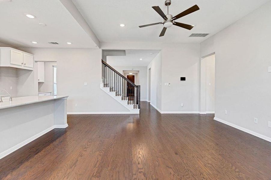 Unfurnished living room featuring dark wood finished floors, recessed lighting, ceiling fan, and stairs Unfurnished living room featuring dark wood finished floors, recessed lighting, ceiling fan, and stairs