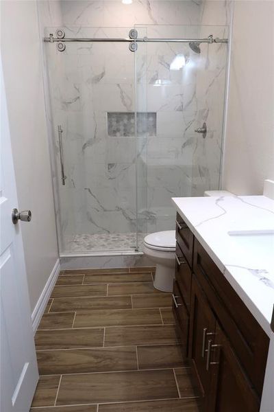 View of second bathroom that is also including glass sliding door, and quartz countertops.