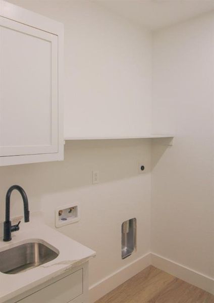 Washroom featuring washer hookup, light wood-style floors, and cabinet space Washroom featuring washer hookup, light wood-style floors, and cabinet space