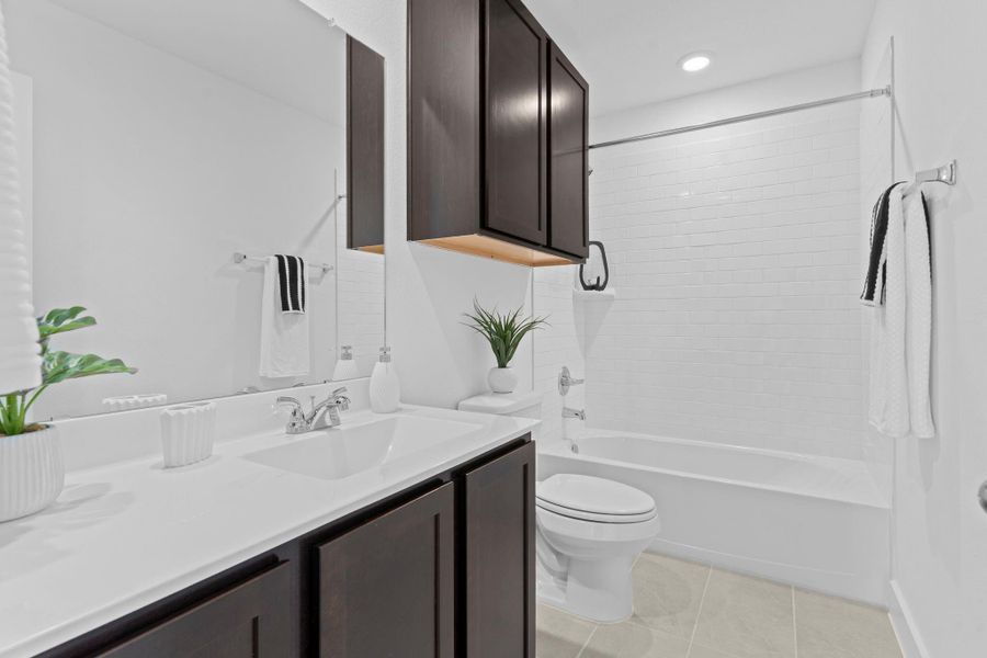 The upstairs bathroom offers a sleek and modern design, complete with a cultured marble countertop, single sink vanity with dark cabinetry, and a crisp white tile tub/shower combo—perfectly blending style and convenience for everyday use. **Image Representative of Plan Only and May Vary as Built**. The upstairs bathroom offers a sleek and modern design, complete with a cultured marble countertop, single sink vanity with dark cabinetry, and a crisp white tile tub/shower combo—perfectly blending style and convenience for everyday use. **Image Representative of Plan Only and May Vary as Built**.