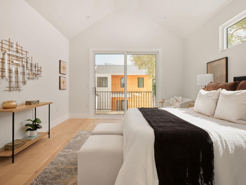Bedroom featuring wood finished floors, multiple windows, lofted ceiling, and access to outside Bedroom featuring wood finished floors, multiple windows, lofted ceiling, and access to outside