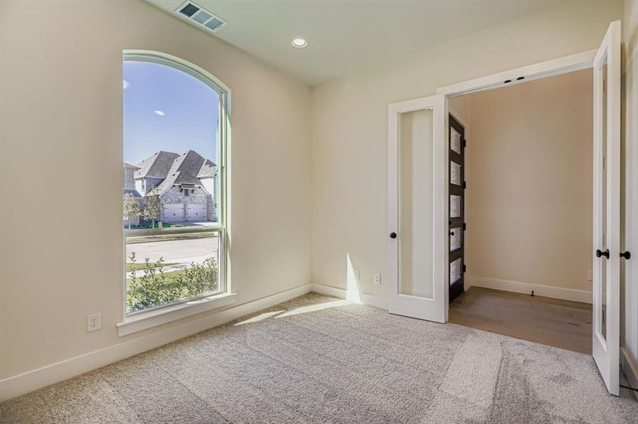 Carpeted empty room with french doors and recessed lighting