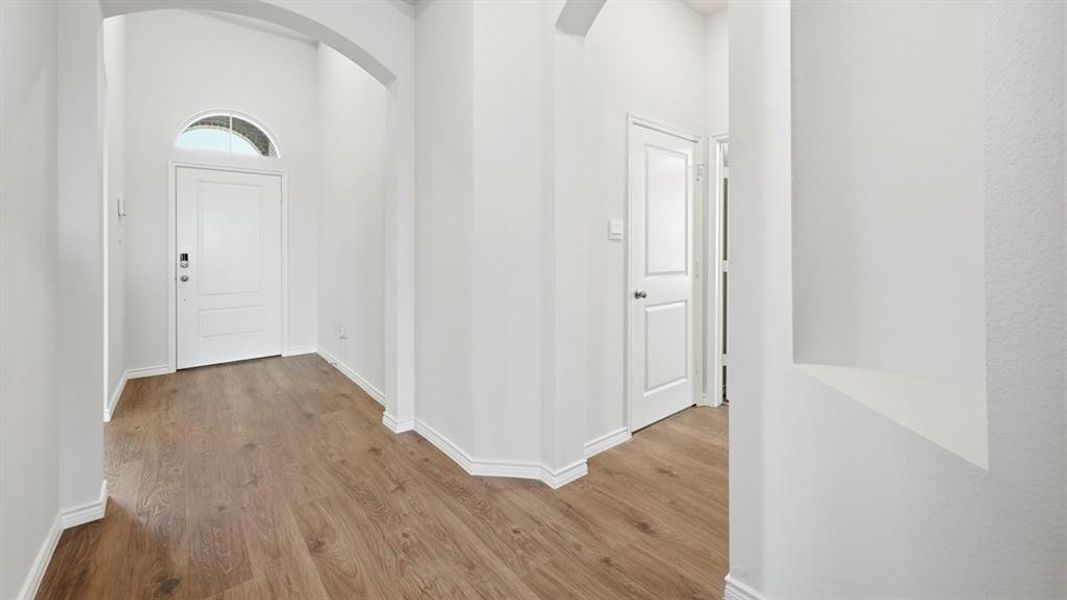Foyer entrance with arched walkways, wood finished floors, and a high ceiling