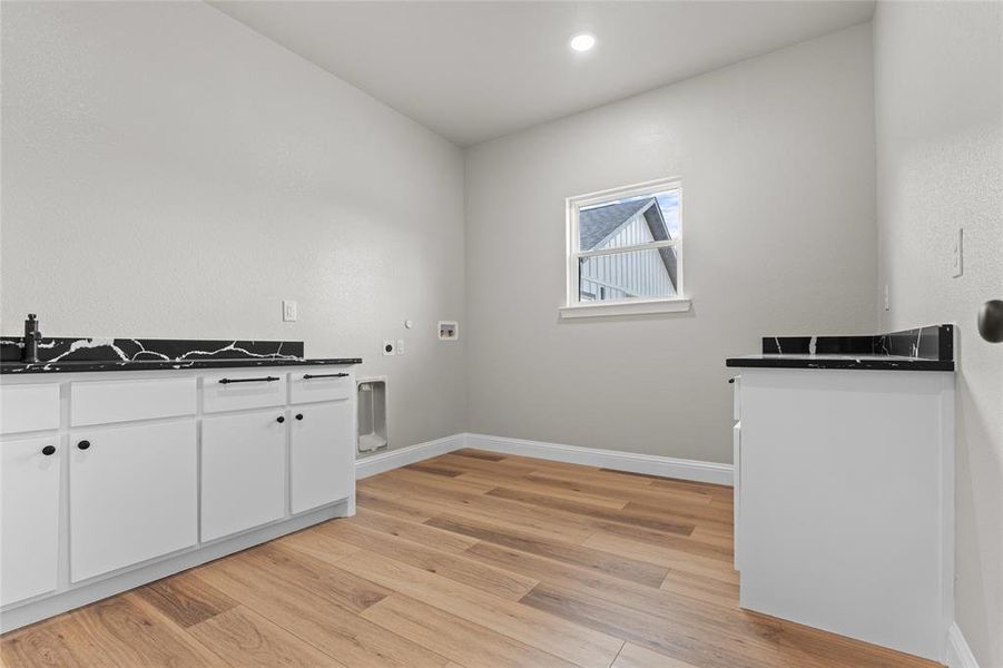 Laundry area featuring washer hookup, electric dryer hookup, light wood finished floors, cabinet space, and hookup for a gas dryer