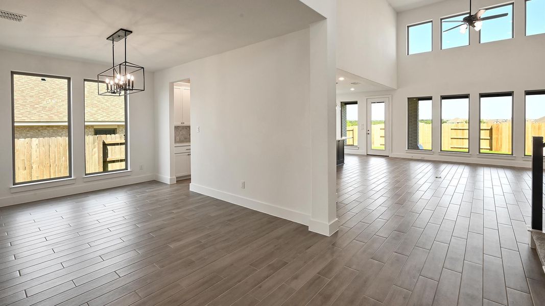 Unfurnished dining area with healthy amount of natural light, a ceiling fan, dark wood-style flooring, and a chandelier