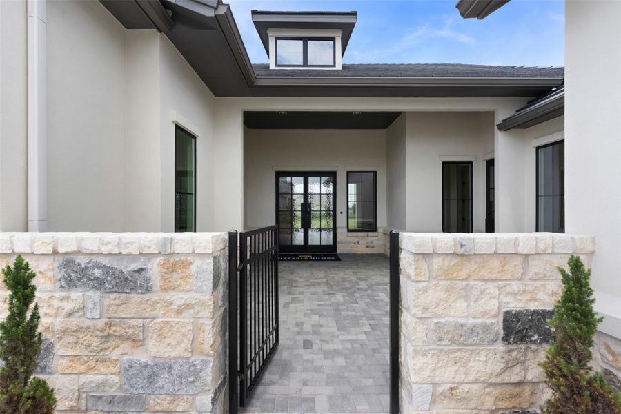 A stone-clad entryway with an iron gate welcomes you to this sophisticated residence.