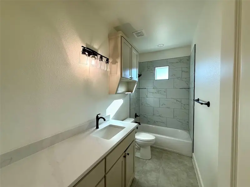 Bathroom featuring vanity, bathing tub / shower combination, and a textured wall