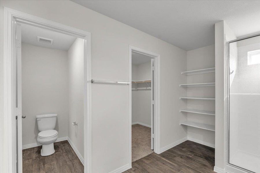 Full bath featuring dark wood finished floors, a stall shower, and a walk in closet