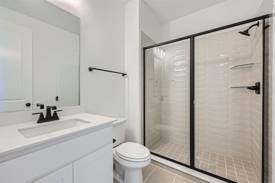 Bathroom with vanity, toilet, an enclosed shower, and tile patterned floors