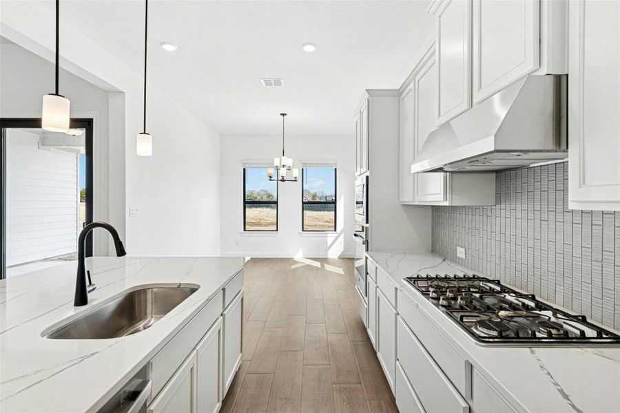 Kitchen featuring light stone counters, light wood-style flooring, white cabinetry, and stainless steel appliances