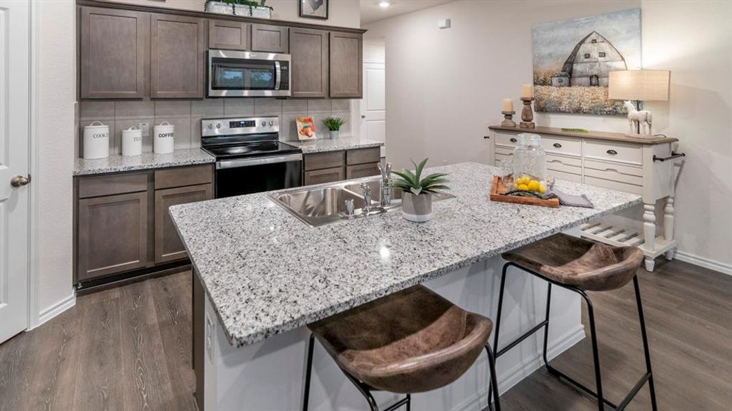 Kitchen with a kitchen bar, stainless steel appliances, light stone countertops, and recessed lighting