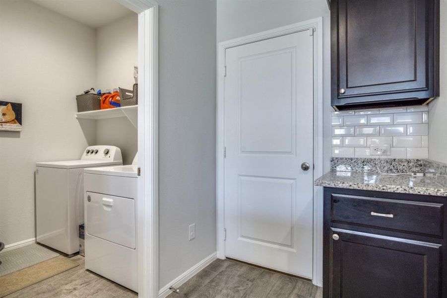 Laundry area with light wood-type flooring, baseboards, laundry area, and washing machine and clothes dryer