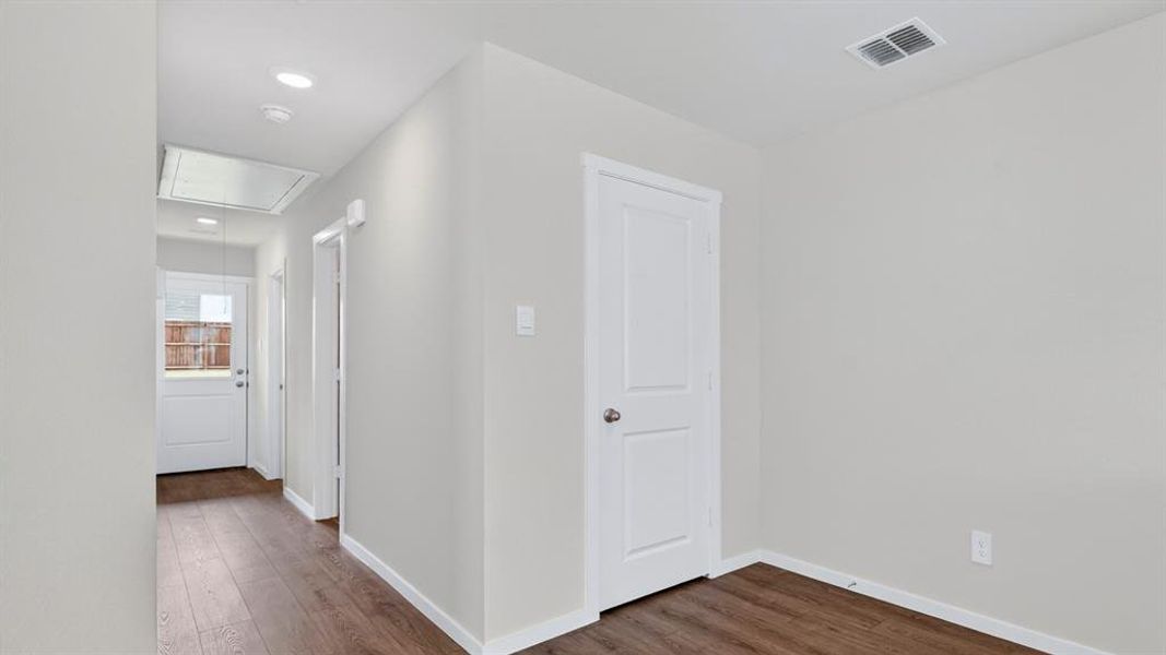 Hallway featuring wood-finish flooring, recessed lighting, and a white paneled door