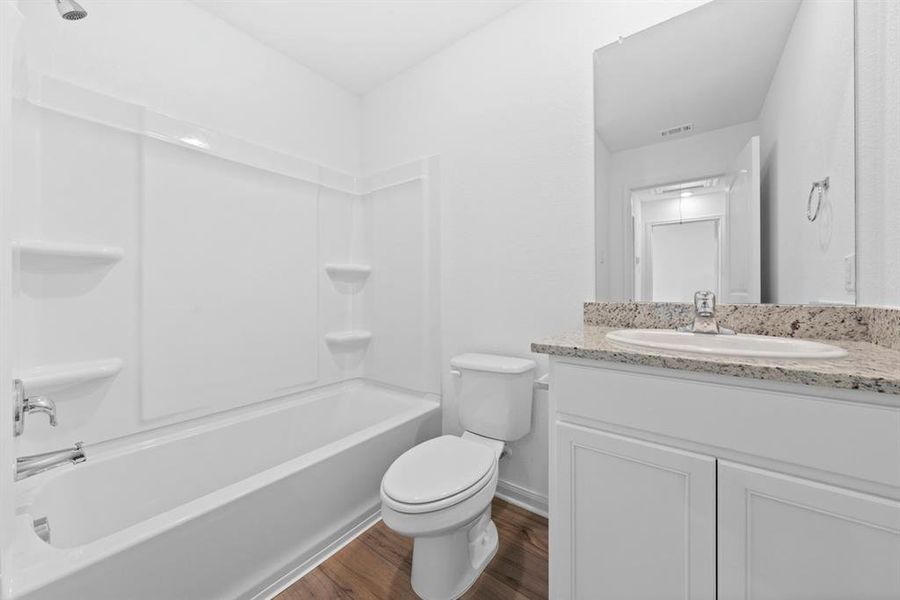 Secondary bathroom includes granite counters, designer white cabinetry and luxury vinyl plank flooring.