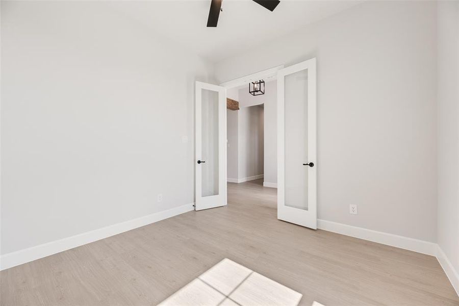 Unfurnished room featuring light wood finished floors, french doors, and ceiling fan