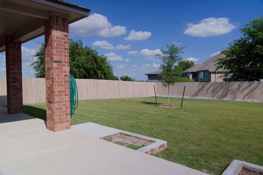 A spacious backyard with mature landscaping and a privacy fence creates an ideal outdoor sanctuary.