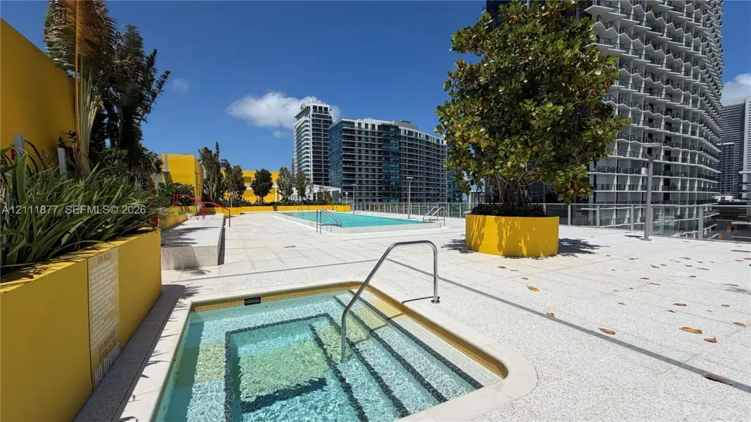 Rooftop deck featuring a swimming pool, recessed spa, integrated concrete planters, and light-toned aggregate hardscaping