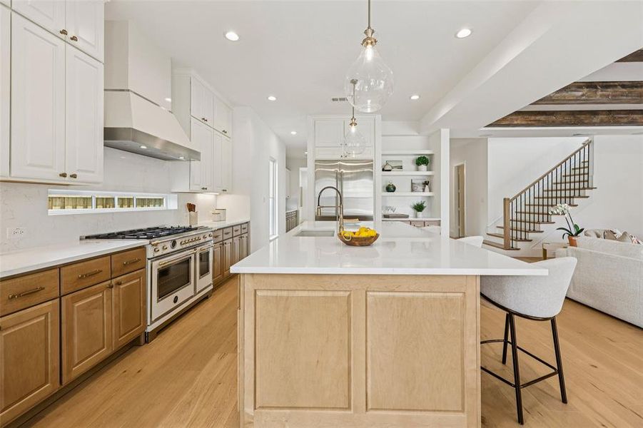 Gourmet kitchen featuring a sizable island with a quartz countertop, professional-grade range, custom cabinetry, recessed lighting, and wood-finish flooring