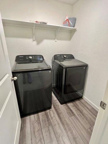 Laundry room with washing machine and dryer and light wood-type flooring