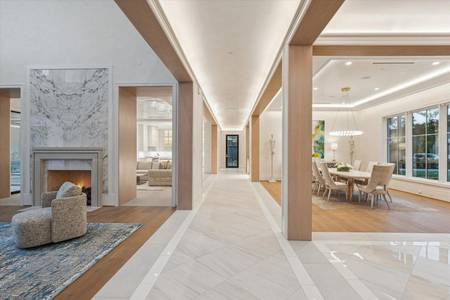 A central hallway defined by clean lines and architectural simplicity, featuring large-format Italian porcelain floors and White-Oak Rift Sawn that elegantly frame the transitions into the formal living and dining rooms.