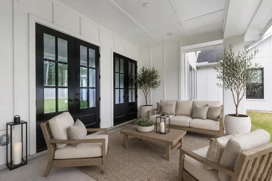 Covered patio extends the living experience outdoors with room for lounging, dining, and enjoying the private backyard. Black framed doors connect the patio to the home’s interior living zones.