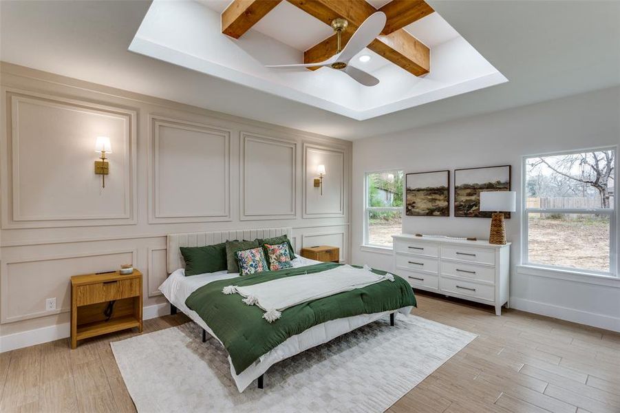 Bedroom featuring multiple windows, light hardwood / wood-style flooring, coffered ceiling, and beamed ceiling