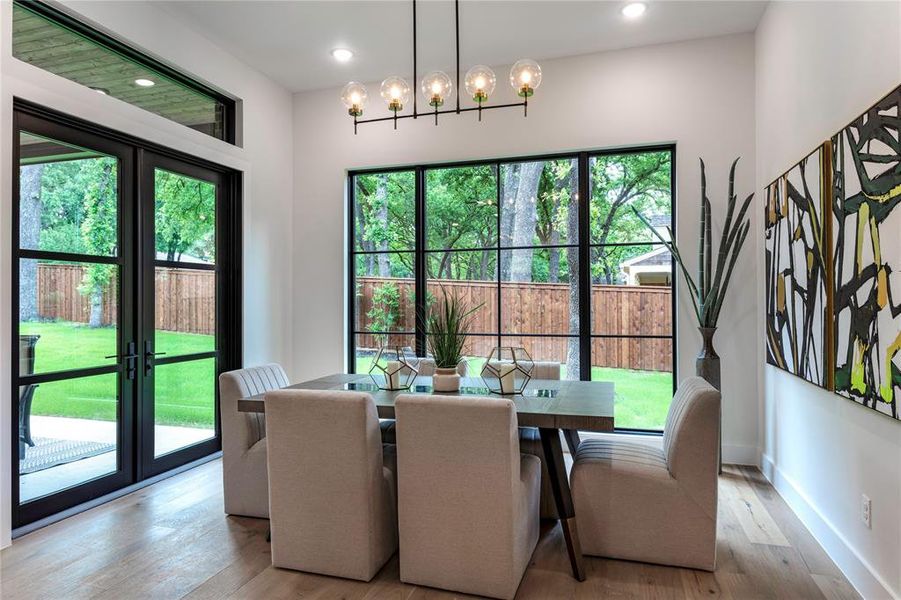 Dining area featuring a chandelier, french doors, light hardwood / wood-style flooring, and a healthy amount of sunlight