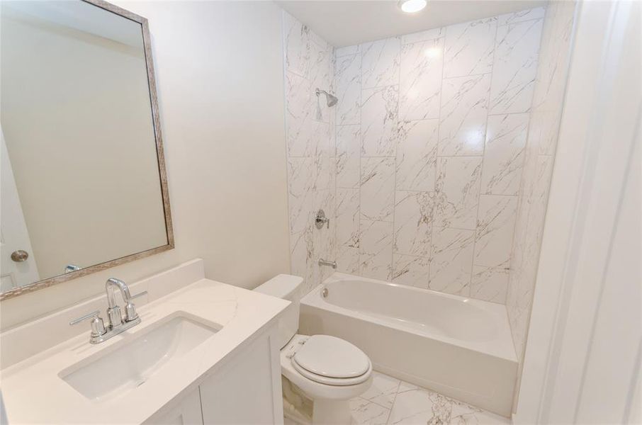 Full bathroom with vanity, tiled shower / bath combo, and toilet