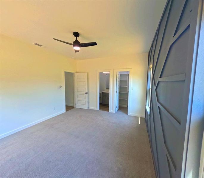Unfurnished bedroom featuring a walk in closet, carpet floors, a ceiling fan, and ensuite bathroom Unfurnished bedroom featuring a walk in closet, carpet floors, a ceiling fan, and ensuite bathroom