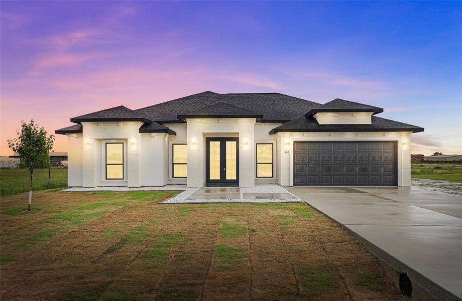 French country style house featuring french doors, driveway, a garage, stucco siding, and a shingled roof French country style house featuring french doors, driveway, a garage, stucco siding, and a shingled roof