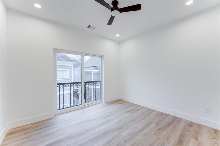 Elegant and serene secondary bedroom with recessed lighting, ceiling fan, and sliding door to balcony.