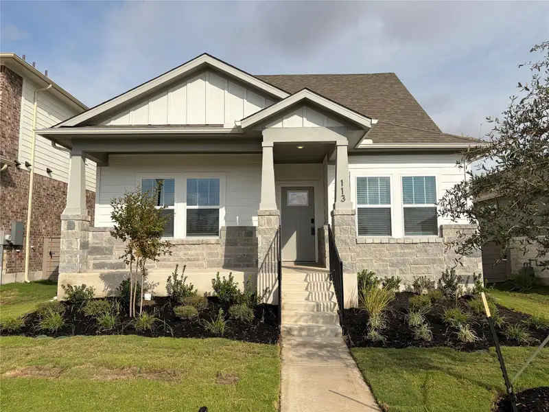 Craftsman-style house with a front yard, stone siding, board and batten siding, and a shingled roof Craftsman-style house with a front yard, stone siding, board and batten siding, and a shingled roof