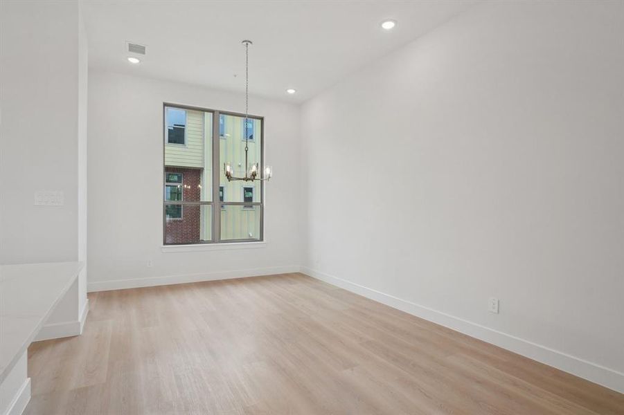 Unfurnished dining area with light wood-style flooring, a chandelier, and recessed lighting