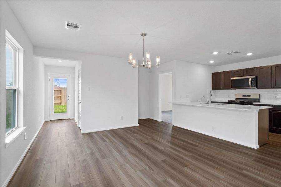 Start your day with a warm cup of coffee and quality time in this charming dining area! Highlights include a large window, custom neutral paint, vinyl plank flooring, high ceilings, gorgeous chandelier fixture, and a convenient door leading to the rear patio and backyard.