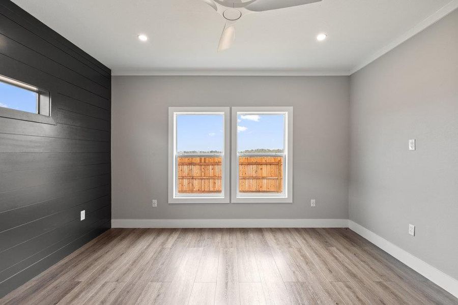 Spare room with wooden walls, light wood-type flooring, an accent wall, and recessed lighting