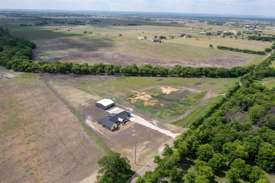 The property includes a single-story residence with a dark gray roof and a detached building with a light-colored roof