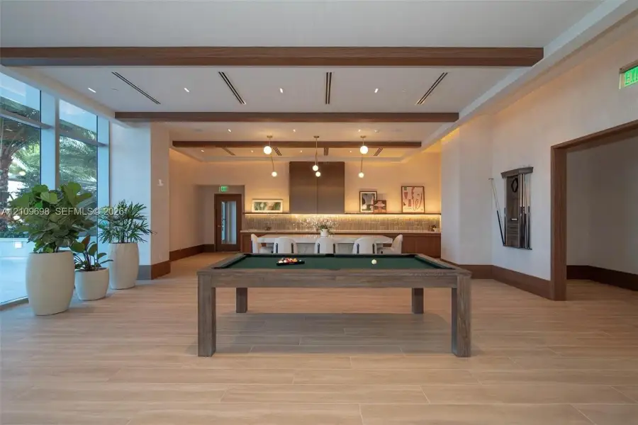 Open floor plan featuring wood-finish flooring, coffered ceiling with exposed wood beams, recessed lighting, and large glass windows