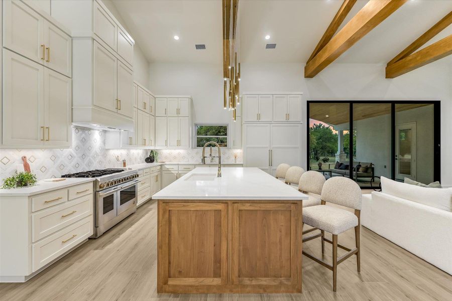 Kitchen with an island with sink, double oven range, a breakfast bar, open floor plan, and tasteful backsplash