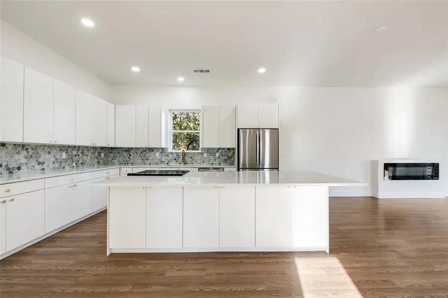 Kitchen with white cabinets, a spacious island, recessed lighting, freestanding refrigerator, and dark wood-type flooring Kitchen with white cabinets, a spacious island, recessed lighting, freestanding refrigerator, and dark wood-type flooring