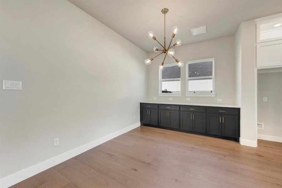 Unfurnished dining area with light wood finished floors, a chandelier, and lofted ceiling Unfurnished dining area with light wood finished floors, a chandelier, and lofted ceiling