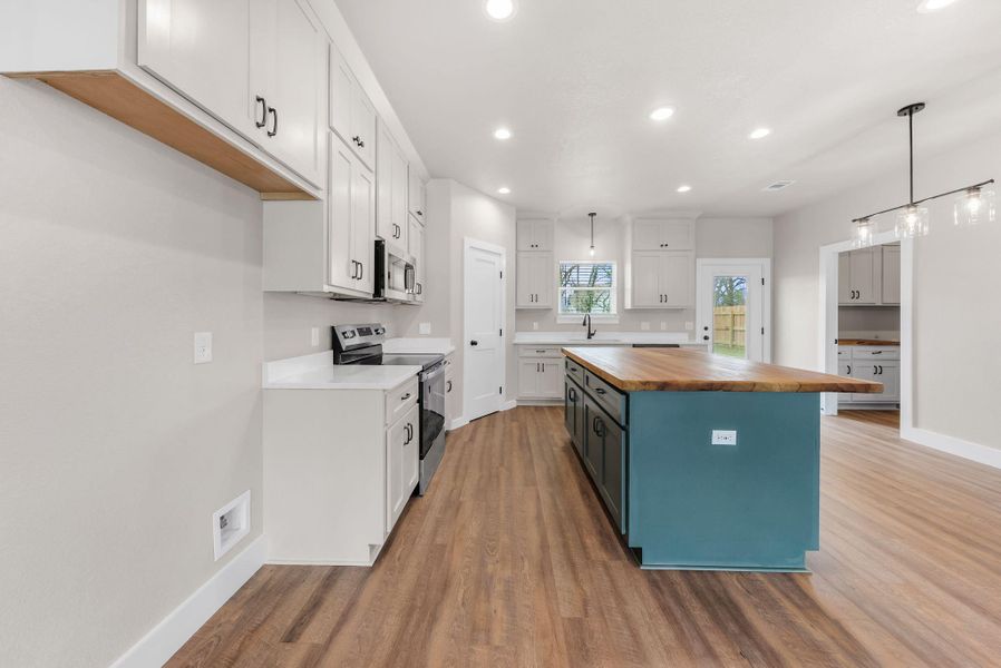 Dual tone kitchen featuring two tone cabinets, stainless steel appliances, butcher block countertops, a kitchen island, and dark wood-style flooring