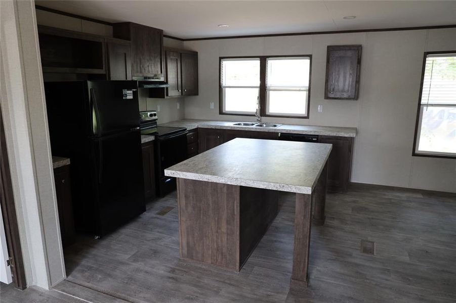 Kitchen with black appliances, range hood, hardwood / wood-style flooring, and a kitchen island